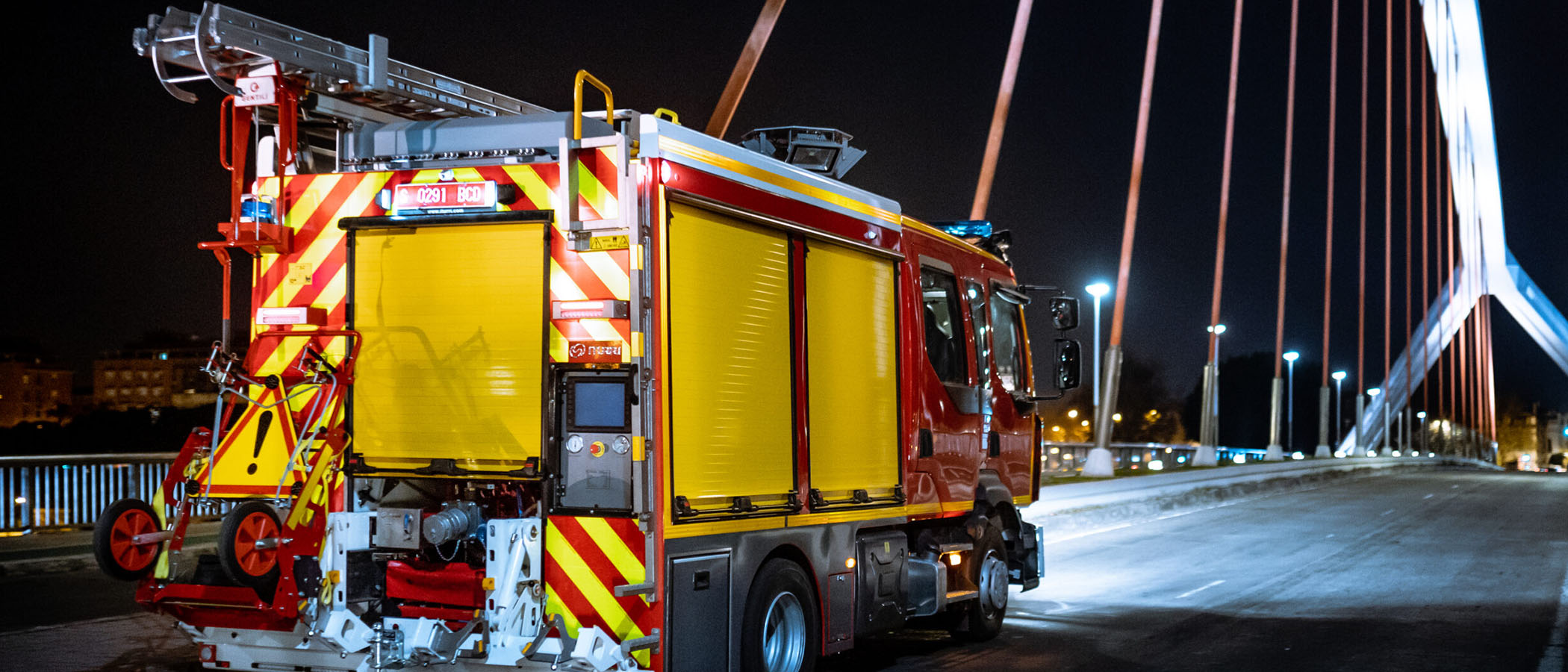 Ein rotes ITURRI Feuerwehrauto, welches bei Nacht über eine Brücke fährt